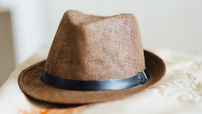 A mens hat resting on fabric. trilby